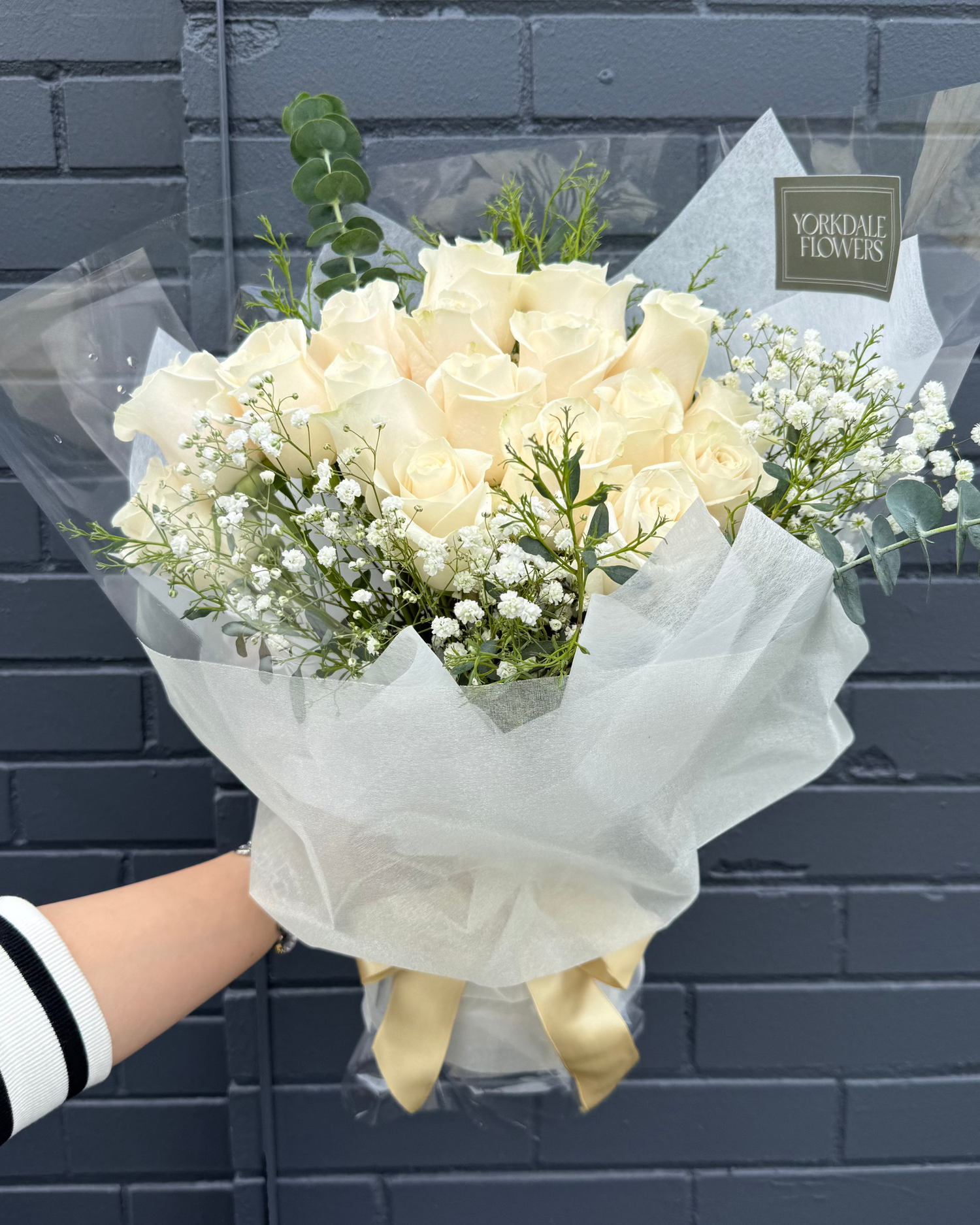 Bouquet of white roses with greenery in a white elegant wrapping.