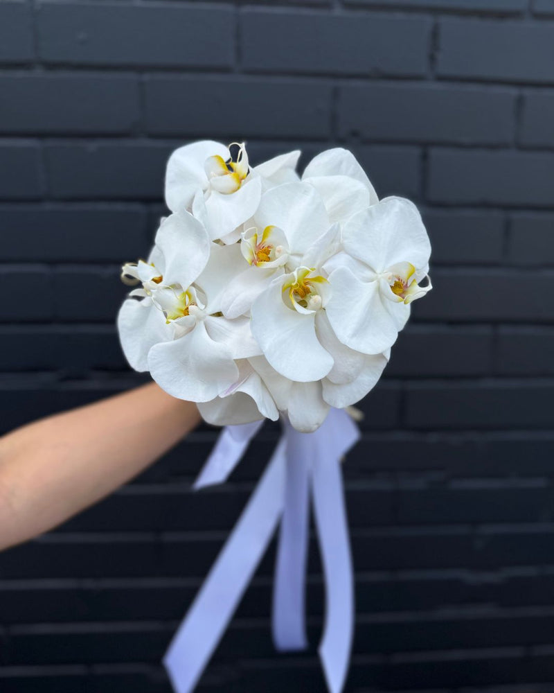 Delicate white orchid bouquet for bride with white ribbon accent