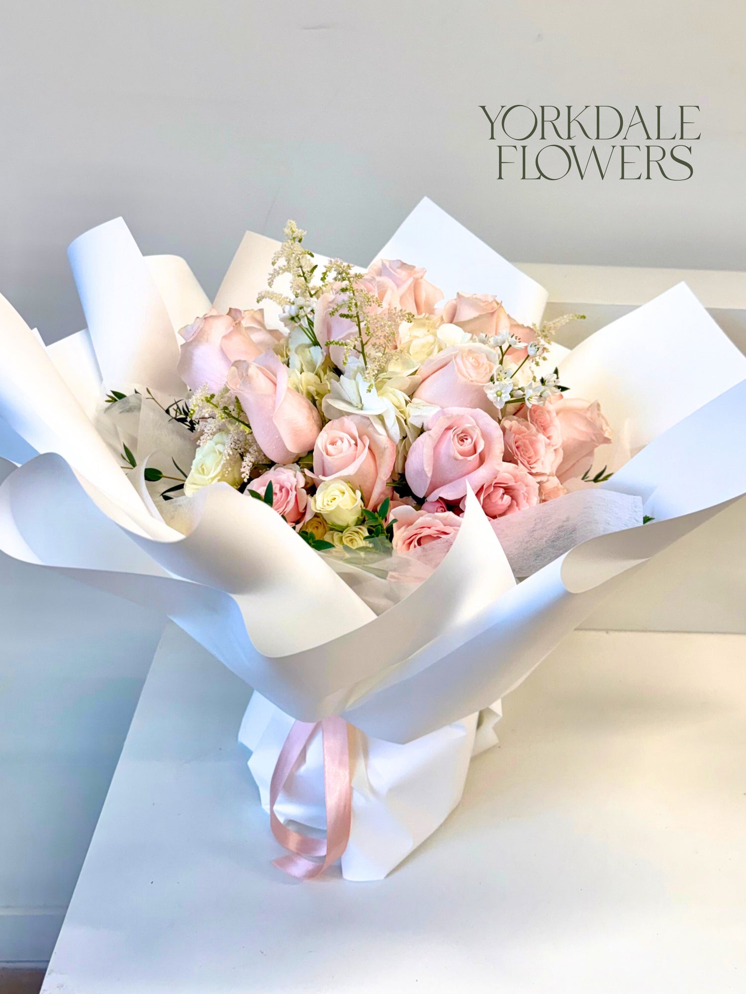 light pink and white roses bouquet in white wrapping