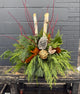 Decorative winter planter arrangement of greenery, pinecones, and branches.