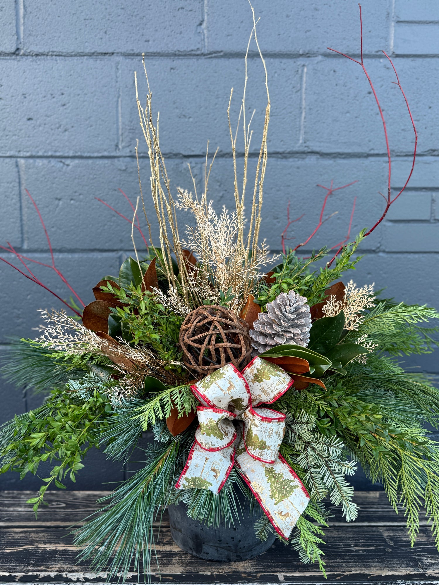 Winter planter decorated with sparkling gold accents, red bow and verdant evergreens.