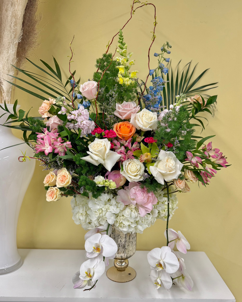 Florar arrangement whit mix of vibrant blooms in a vintage vase.