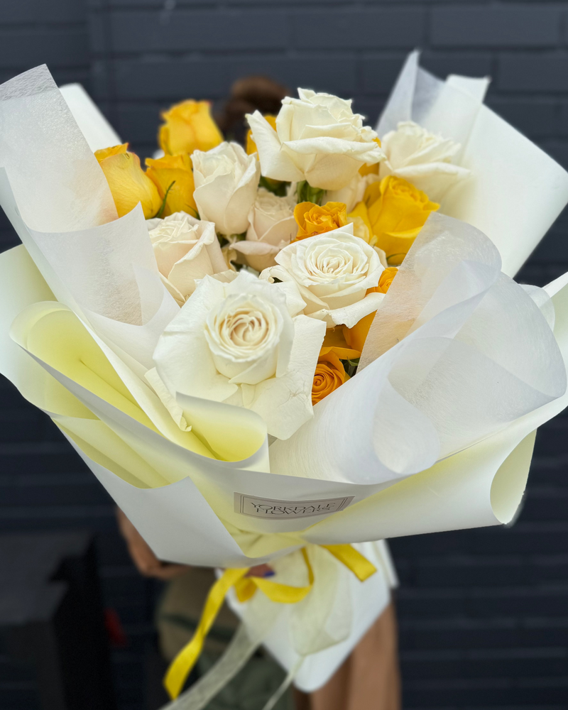Yellow and soft white roses bouquet wrapped in a light yellow paper.