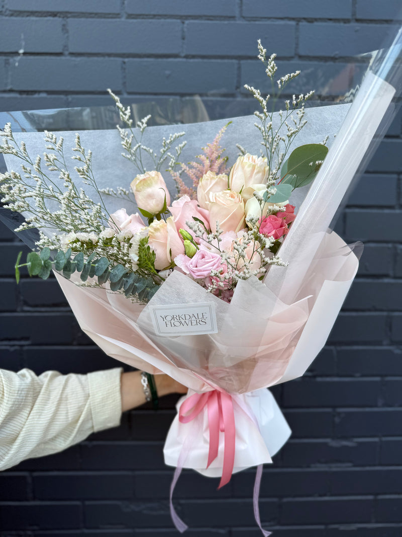 Bouquet palette of peach and blush roses wrapped in a white and peach paper.