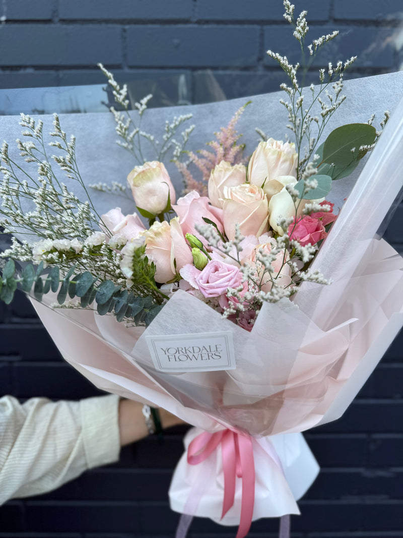 Bouquet palette of peach and blush roses wrapped in a white and peach paper.