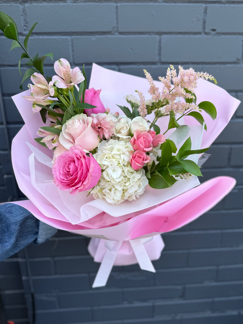 Bouquet whit mix of white hydrangea,  pink and blush roses wrapped in a pink paper.