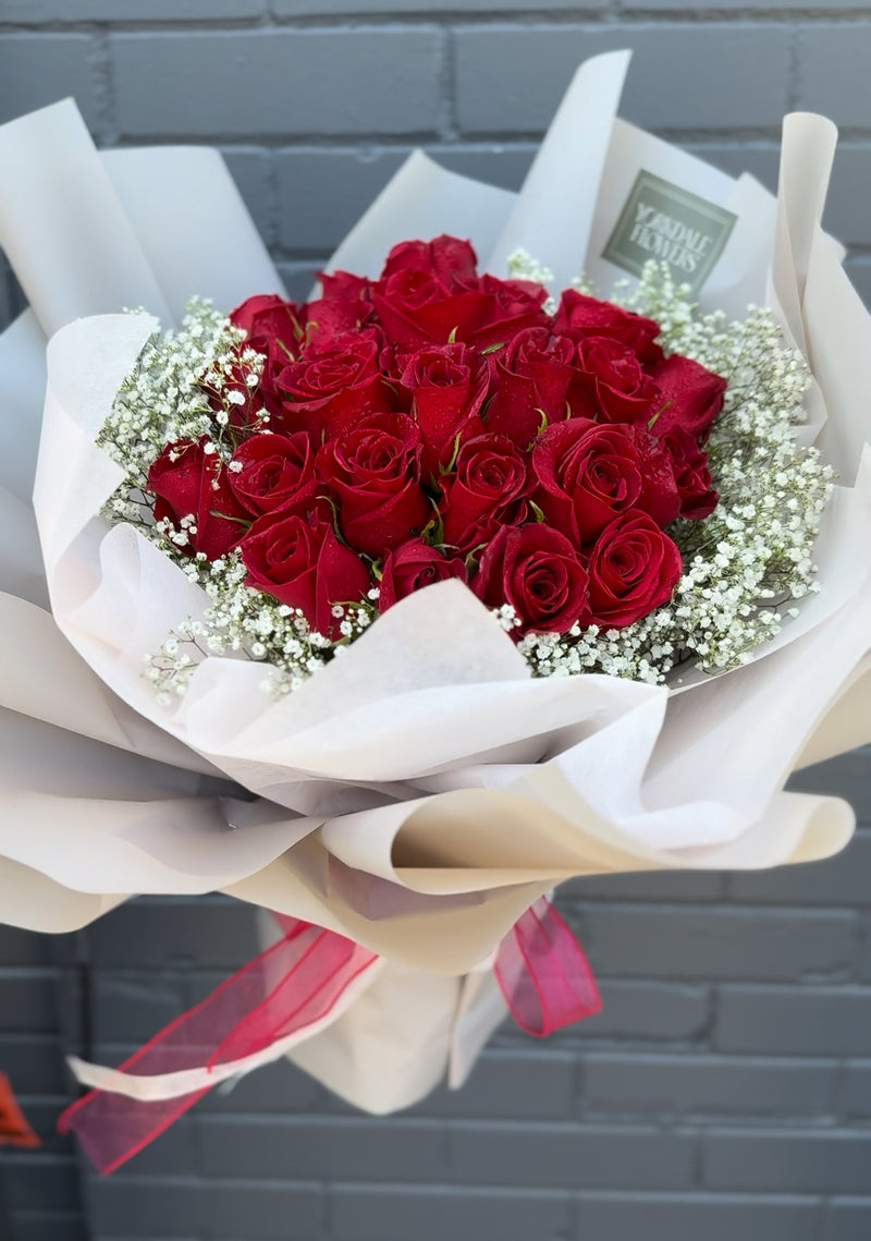 Red roses bouquet with baby's breath wrapped with a white paper.