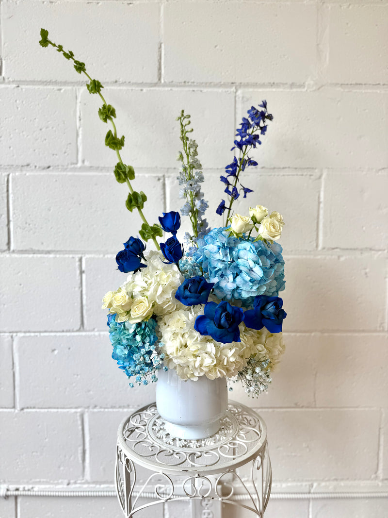 Stunning deep blue and white floral centrepiece in a white vase.