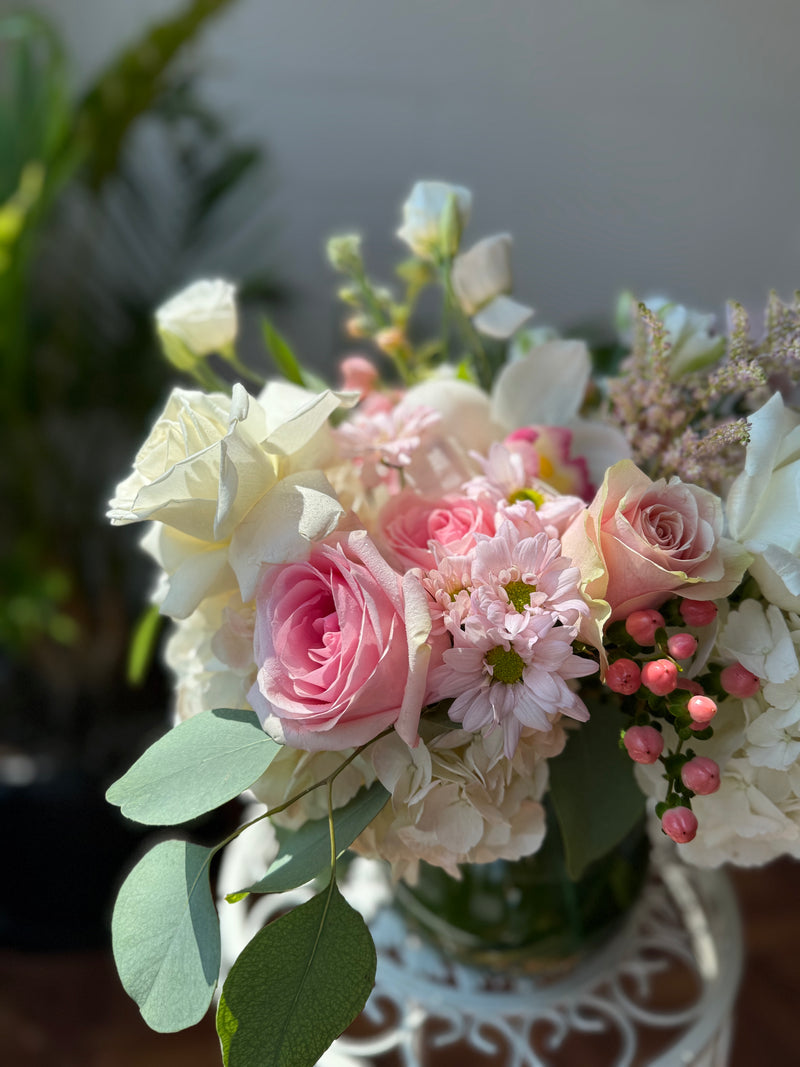 Florar arrangement with white and pink flowers in a clear vase.