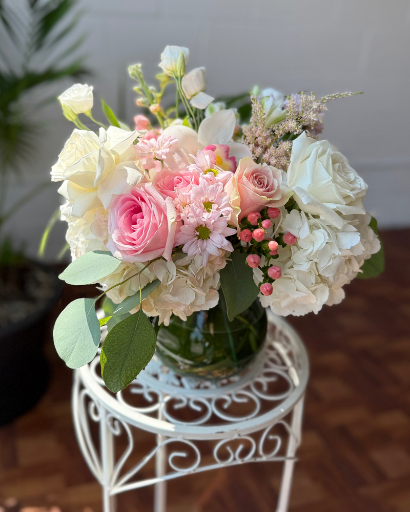 Florar arrangement with white and pink flowers in a clear vase.