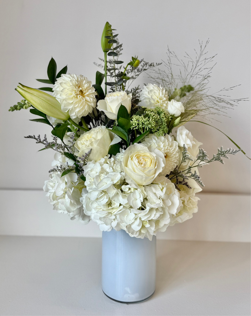 Elegant floral arrangement with white flowers and greenery in a clear crystal vase – centrepiece or home decor.