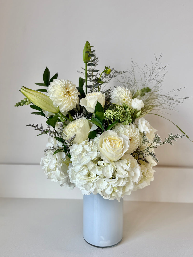 Elegant floral arrangement with white flowers and greenery in a clear crystal vase – centrepiece or home decor.