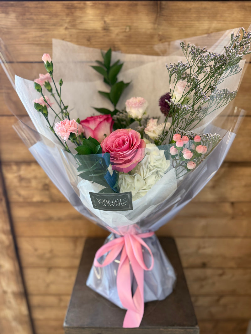 Floral bouquet with white petals and vivid pink accents, wrapped in light gray paper with bright pink ribbon – cheerful gift arrangement.