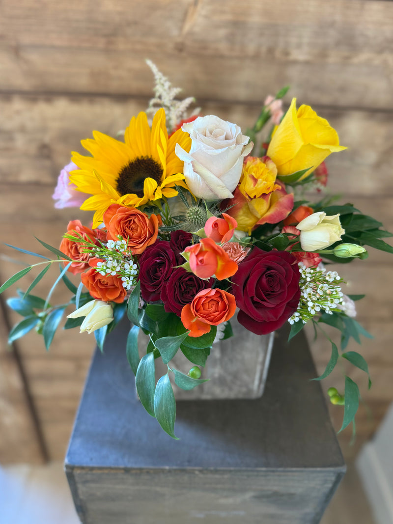 Rustic fall bouquet in warm autumn shades arranged in a silver square vase.