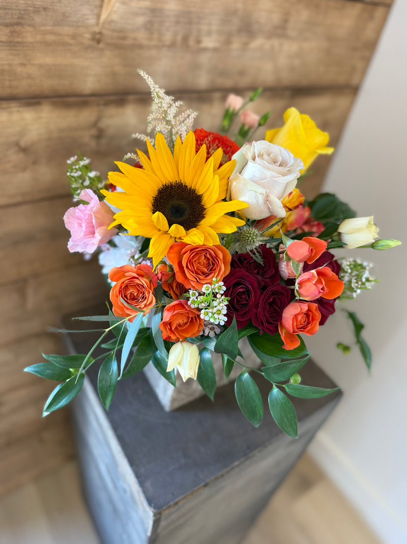 Rustic fall bouquet in warm autumn shades arranged in a silver square vase.