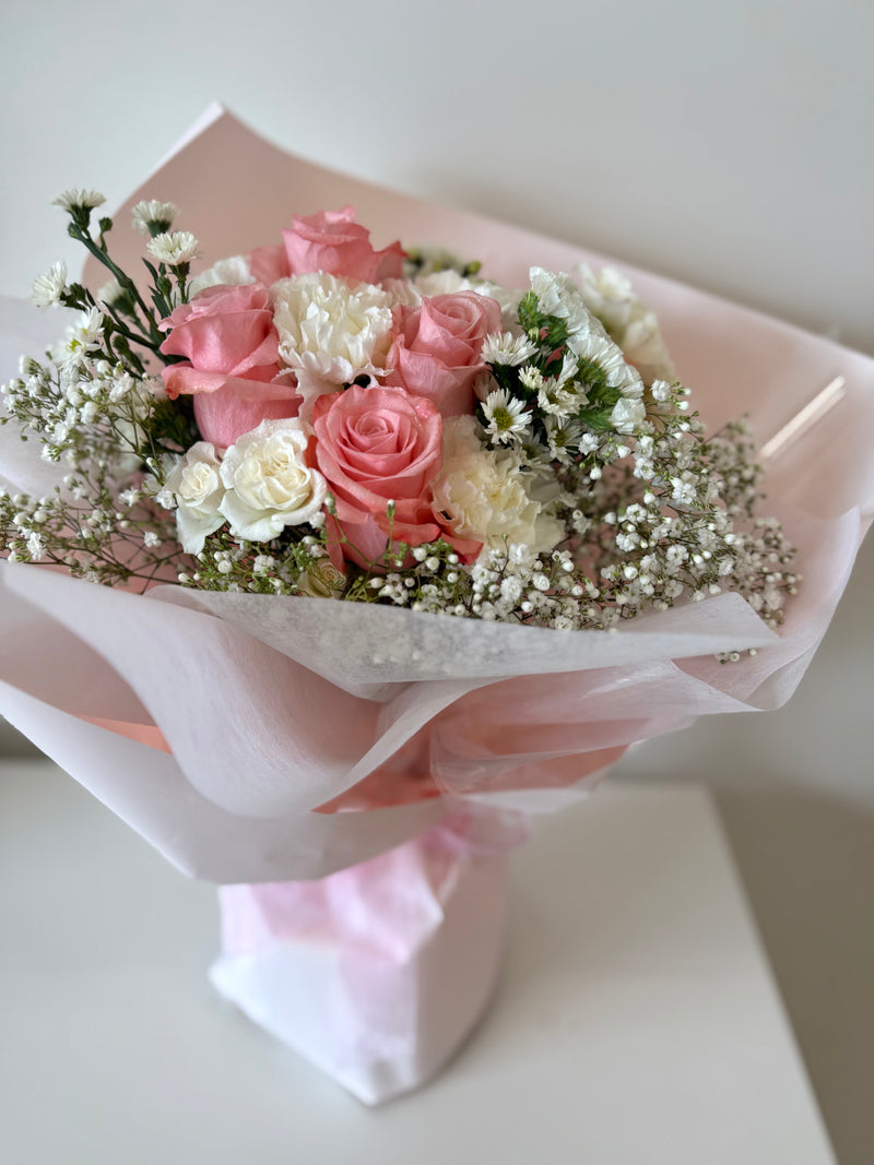 Soft pink roses mixed with white flowers, wrapped in a light pink paper.