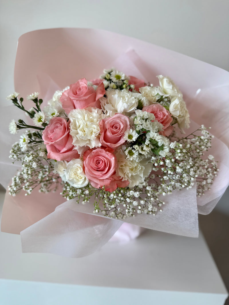 Soft pink roses mixed with white flowers, wrapped in a light pink paper.