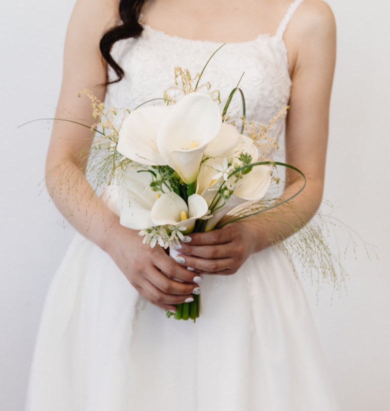 Bridal bouquet with white calla lilies, elegantly arranged with a refined silhouette.