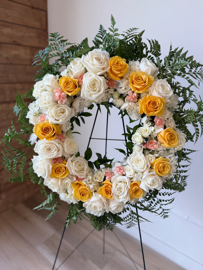 Floral wreath with white, yellow, and pink roses.