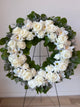 Floral wreath with white flowers and green leaves.