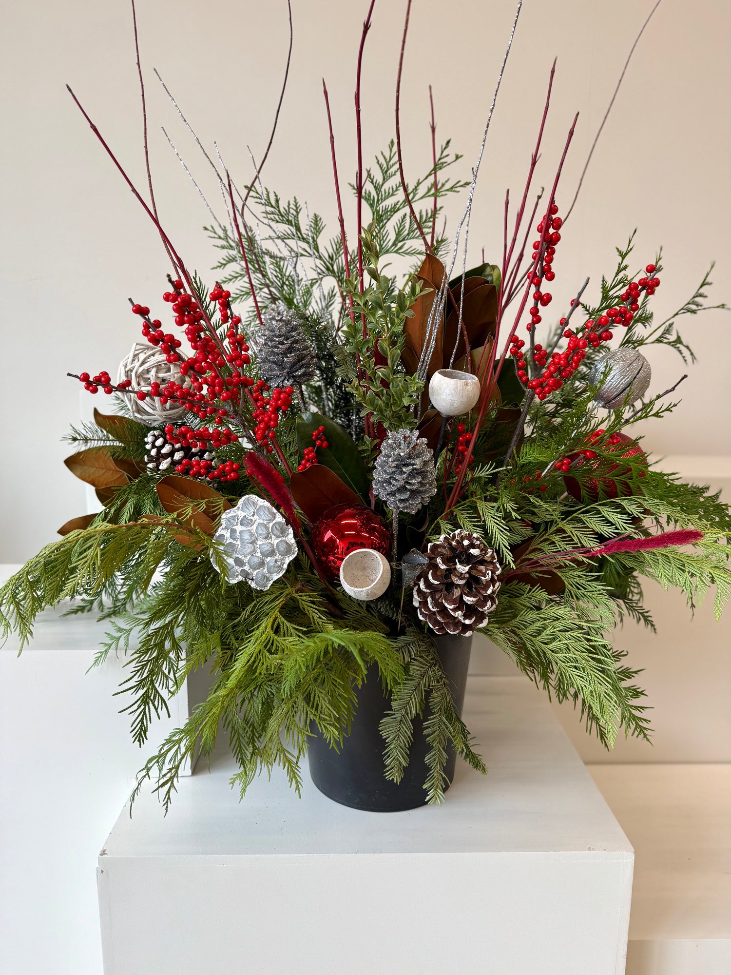 Winter planter decorated with ilex, sparkling silver accents, and verdant evergreens.