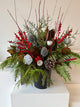 Winter planter decorated with ilex, sparkling silver accents, and verdant evergreens.