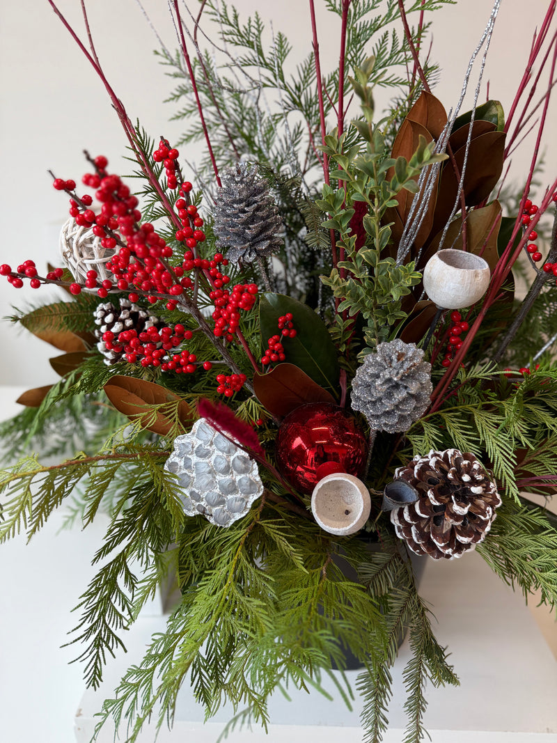 Winter planter decorated with ilex, sparkling silver accents, and verdant evergreens.