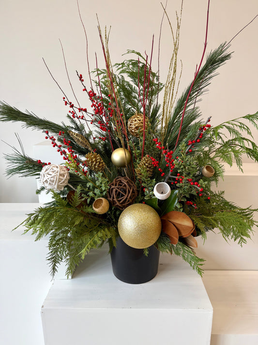 Winter planter decorated with ilex, sparkling gold accents, and verdant evergreens.