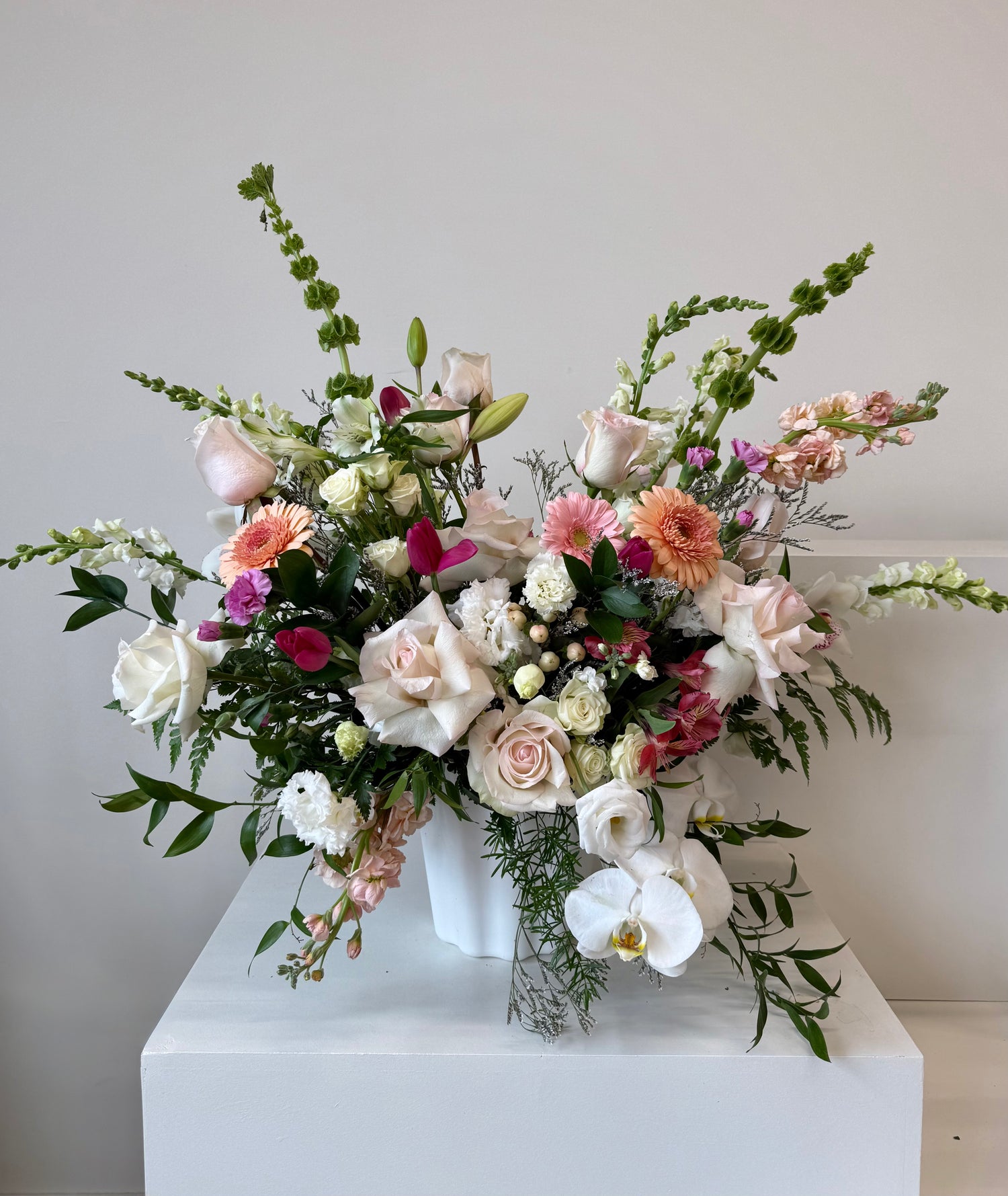 Floral arrangement peach and blush blooms arranged in a white vase.