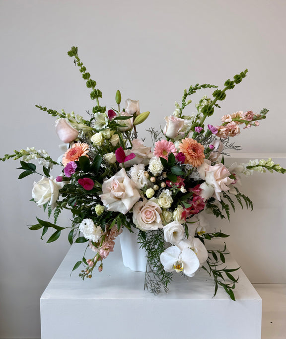 Floral arrangement peach and blush blooms arranged in a white vase.