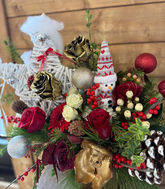 Decorative floral arrangement with Christmas-themed elements in a gold vase.