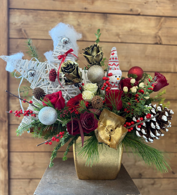 Decorative floral arrangement with Christmas-themed elements in a gold vase.