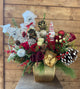 Decorative floral arrangement with Christmas-themed elements in a gold vase.