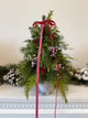 Handcrafted small Christmas tree arrangement featuring festive greenery and red ribbon accents—perfect for holiday décor.
