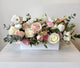 White and blush pink flower arrangement in long white container