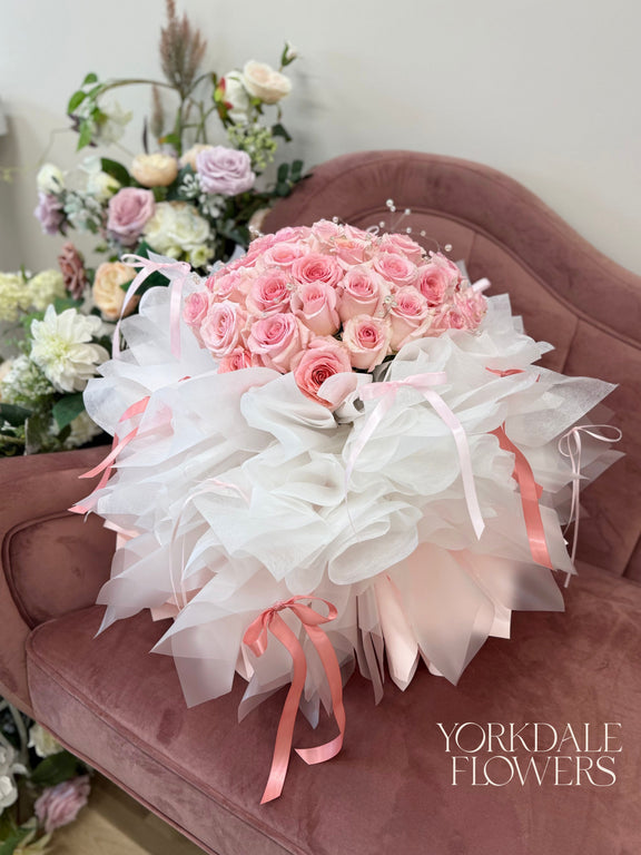 bouquet of pink roses with lush white and light pink wrapping