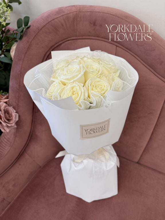 Bouquet of white roses wrapped in white paper
