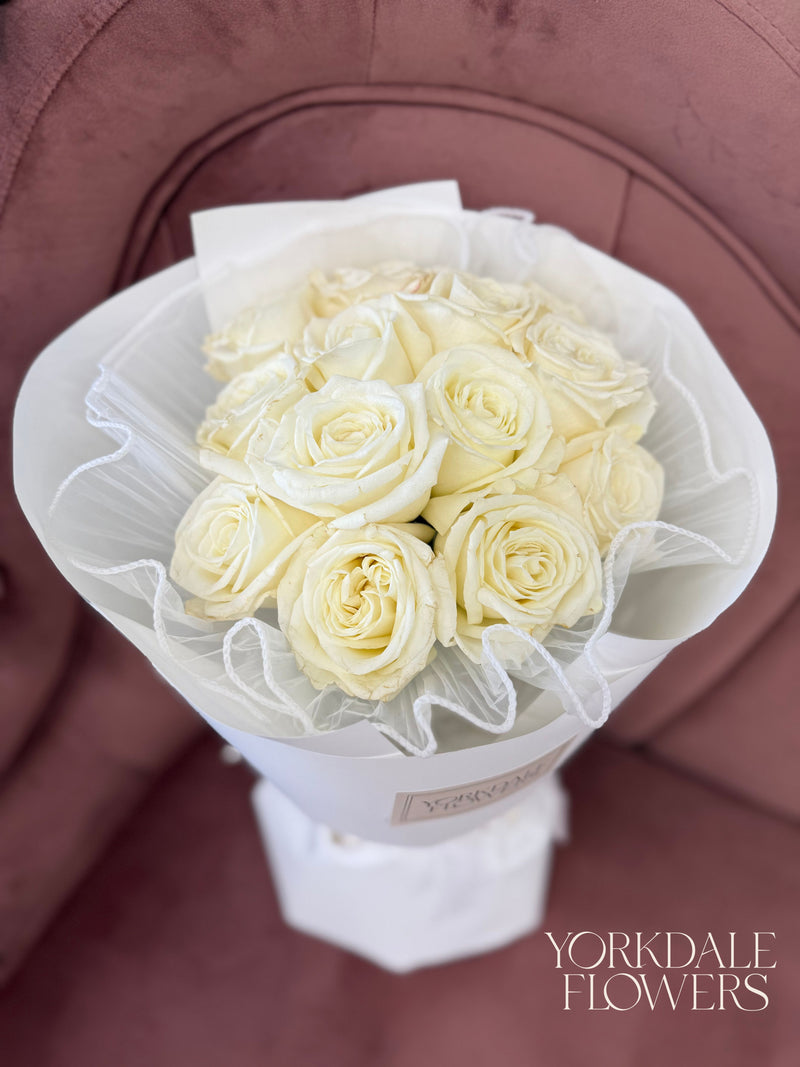 Bouquet of white roses wrapped in white paper