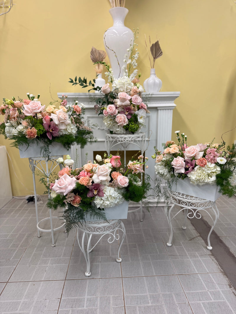 Complete set of floral centrepieces with soft pink and peach flowers and textured greenery.