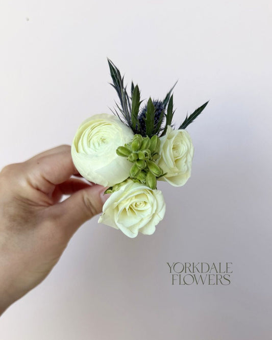 white ranunculus and white rose boutonniere